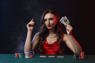 Siyah arka planda poker oynayan hoş bir kadın.