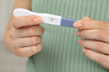 Kapalı alanda hamilelik testi tutan kadın, yakın çekim.