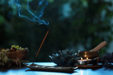 Tütsü tutacakta, yanan mumlar, kuru çiçekler ve açık havada Tibet şarkı kasesi.