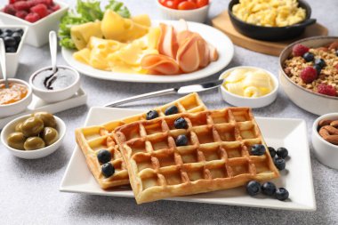 Lezzetli bir kahvaltı. Belçika waffle 'ı, yaban mersini ve diğer yiyecekler gri desenli masada, yakın plan.