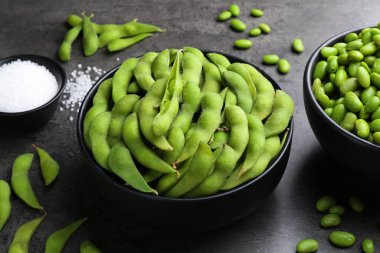 Çiğ yeşil edamame soya fasulyesi ve gri masadaki kabuklar.