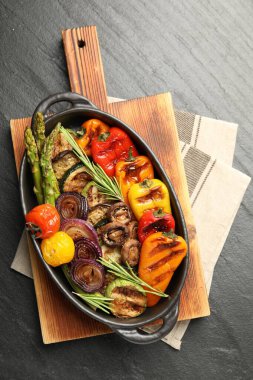 Gri desenli masada, fırında pişirme kabında nefis ızgara sebzeler.