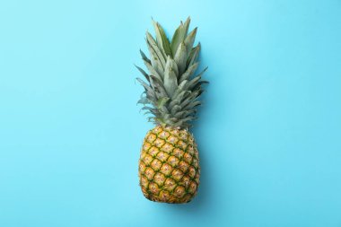 Açık mavi arka planda taze, olgun bir ananas.
