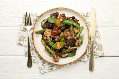 Beyaz ahşap masada servis edilen ızgara sebzeli leziz salata.