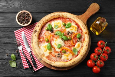 Siyah ahşap masada servis edilen lezzetli vejetaryen pizza.
