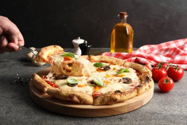 Gri masada lezzetli bir vejetaryen pizzası yiyen adam, yakın plan.