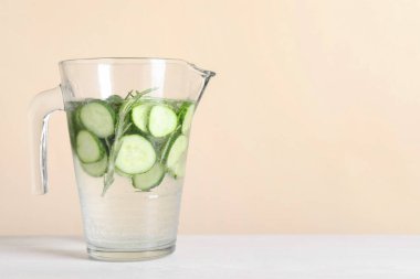 Beyaz masadaki biberiyeli salatalık suyunu bej arka planda yeniliyor. Metin için boşluk