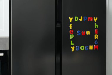 Kelime Güneşi ve çerçeve içerideki buzdolabının üzerinde bir sürü parlak manyetik harften yapılmış. Alfabe öğreniliyor
