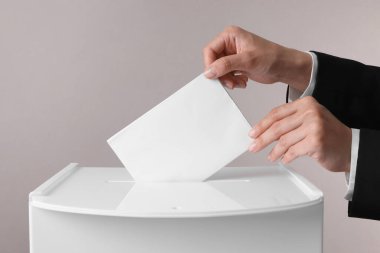 Kadın oyunu gri arka planda sandığa koyuyor, yakın plan.