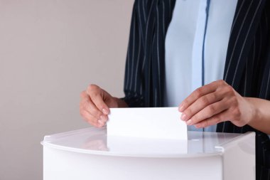 Kadın oyunu gri arka planda sandığa koyuyor, yakın plan.