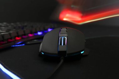 Koyu arkaplanda bilgisayar faresi ve RGB klavyesi, yakın plan