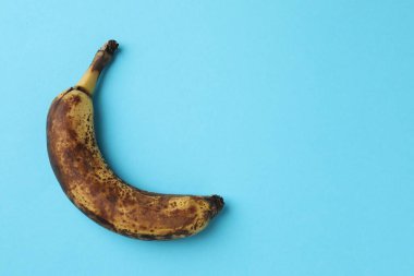 Açık mavi arka planda koyu benekli, olgun bir muz. Metin için boşluk