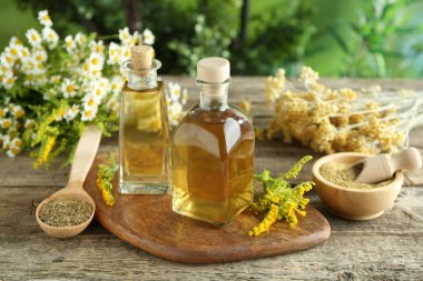 Tinctures in bottles and medicinal herbs on wooden table clipart