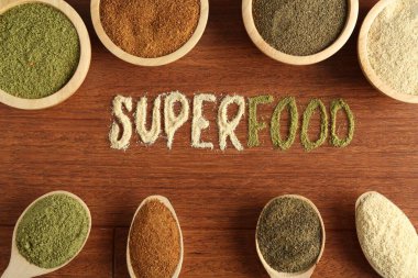 Superfood kelimesi ve ahşap masa üzerindeki farklı sağlıklı tozlar.
