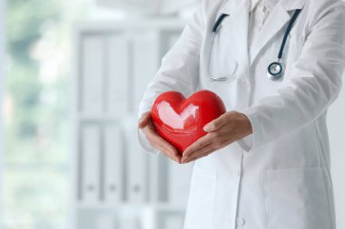 Klinikte kırmızı kalpli bir doktor, yakın plan. Metin için boşluk