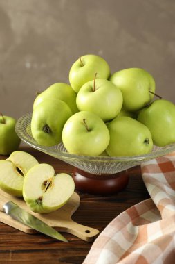 Taze elmalı cam vazo, tahta tahta ve bıçağı gri arka planda, yakın plan.