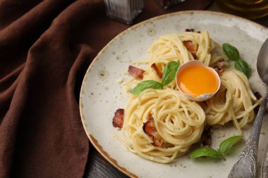 Carbonara makarnası ahşap masada servis edilir, yakın plan.