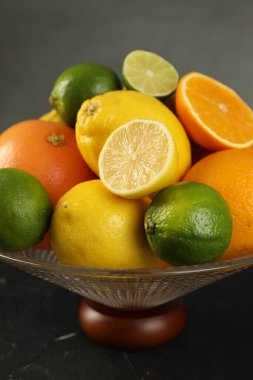 Üzerinde farklı narenciye meyveleri olan cam vazo, yakın plan.