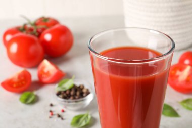 Bardakta lezzetli domates suyu, fesleğen yaprakları ve taze sebzeler, yakın plan.
