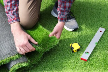 Genç adam yapay çim kuruyor, yakın çekim görüntüsü