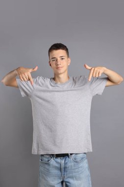 Gri arka planda tişört giyen genç çocuk.