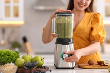 Mutfaktaki beyaz mermer masada blender ile nefis smoothie yapan kadın, yakın plan.