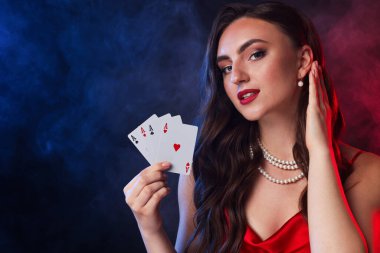Poker oyunu. Siyah arka planda renkli ışıklar ve dumanla iskambil oynayan çekici bir kadın. Metin için boşluk