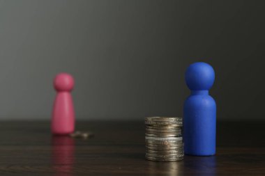 Finansal eşitsizlik. Erkek ve kadın figürleri ahşap masanın üzerinde dengesiz miktarda madeni para var.