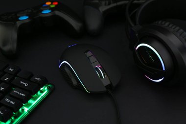 Bilgisayar faresi, kulaklık, RGB klavye ve oyun denetleyicileri siyah arkaplanda, yakın plan