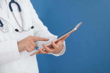 Mavi arkaplanda tableti olan doktor, yakın plan görünümü
