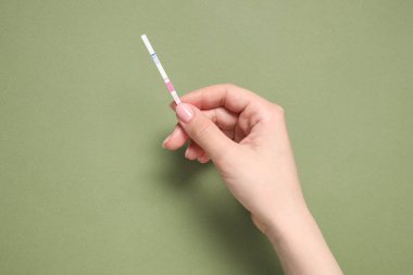 Zeytin arka planında hamilelik testi yapan bir kadın. Metin için boşluk