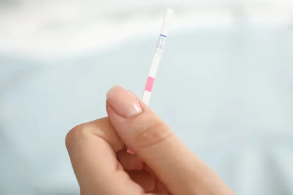 stock image Woman holding pregnancy test indoors, closeup view