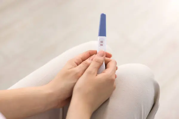 stock image Woman holding pregnancy test in room, closeup