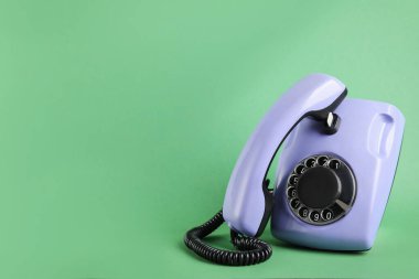 Yeşil arkaplanda cep telefonu olan bir menekşe telefon, metin için boşluk