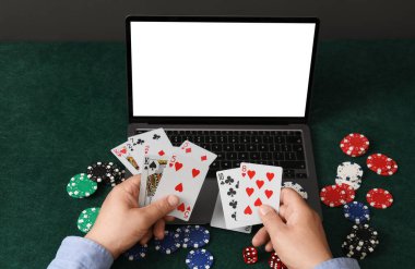 Çevrimiçi poker. Yeşil masada elinde laptoplu ve cipsli kağıt tutan adam, yakın plan.