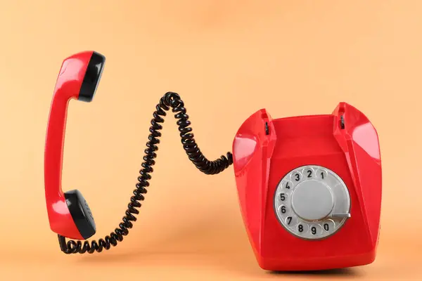 stock image One red telephone with handset on pale orange background