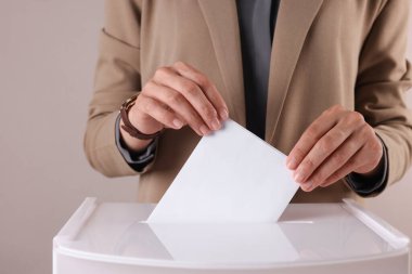 Kadın oyunu gri arka planda sandığa koyuyor, yakın plan.