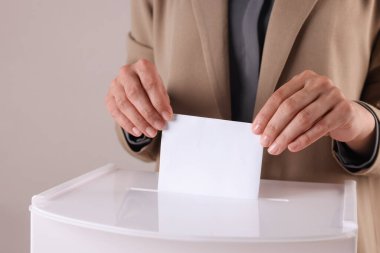 Kadın oyunu gri arka planda sandığa koyuyor, yakın plan.