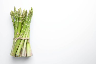 Beyaz masada taze yeşil kuşkonmaz sapları var, üst tarafta. Metin için boşluk