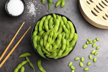 Çiğ yeşil edamame soya fasulyesi ve kapsülleri gri masada, düz yerde.