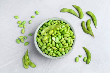 Taze edamame soya fasulyesi kasede ve gri desenli masada kapsüller, düz uzanmış.