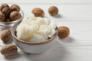 Shea tereyağı kasede ve fındık beyaz ahşap masada, yakın plan.