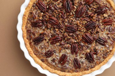 Açık kahverengi arka planda, fırın kabında nefis cevizli turta.