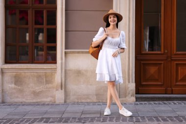 Şehir caddesinde sırt çantalı şık şapkalı güzel bir kadın.