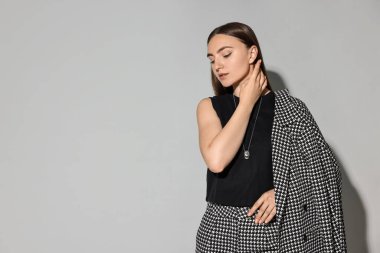 Gri arka planda şık takım elbiseli güzel kadın, mesaj için yer var.