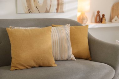 Oturma odasındaki gri koltukta farklı yumuşak yastıklar.