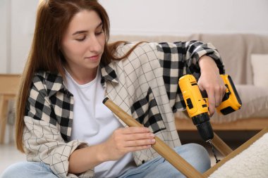 Elektrikli tornavidalı kadın koltuğu evde monte ediyor.