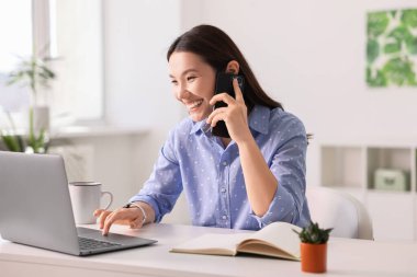Ofiste akıllı telefondan konuşan gülümseyen iş kadını.