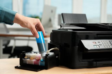 Woman refilling ink in modern printer at workplace indoors, closeup clipart