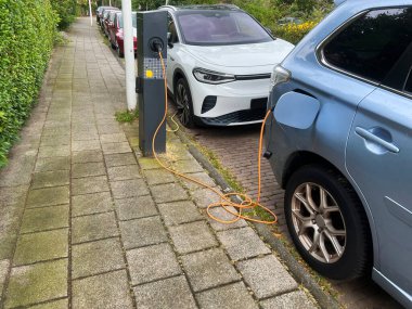 Şehir caddesinde modern elektrikli araba şarj oluyor.